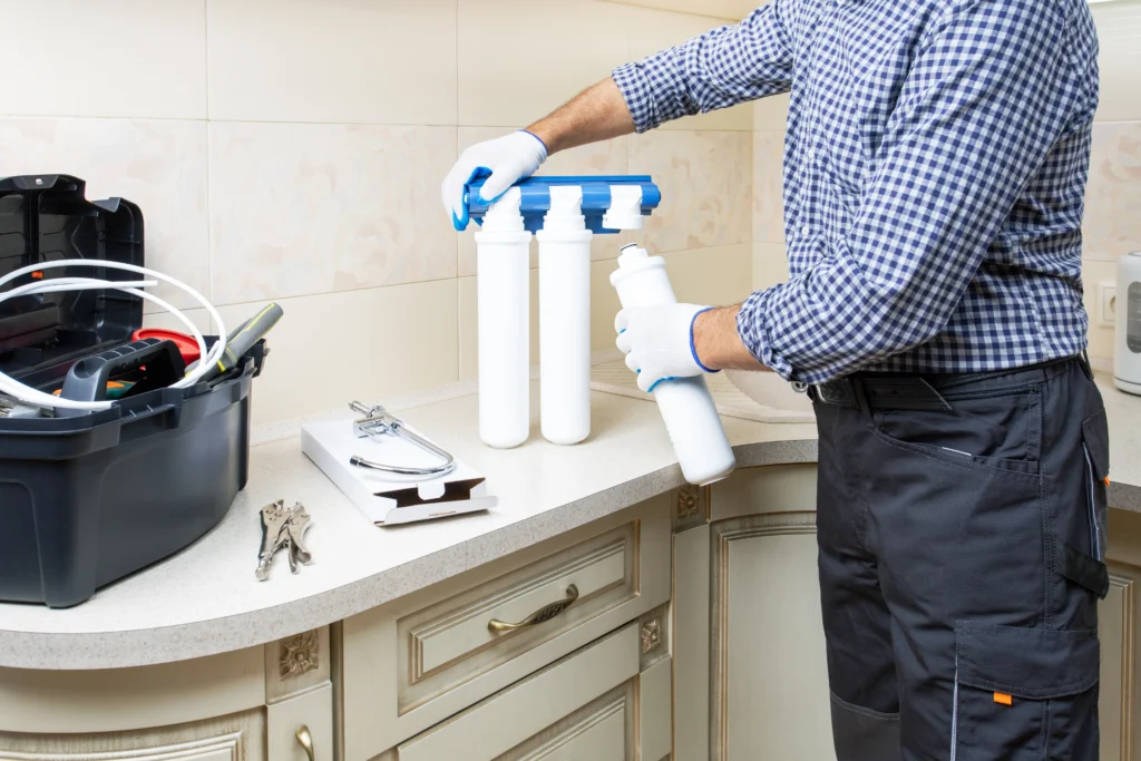Technician replacing under-sink water filter cartridges